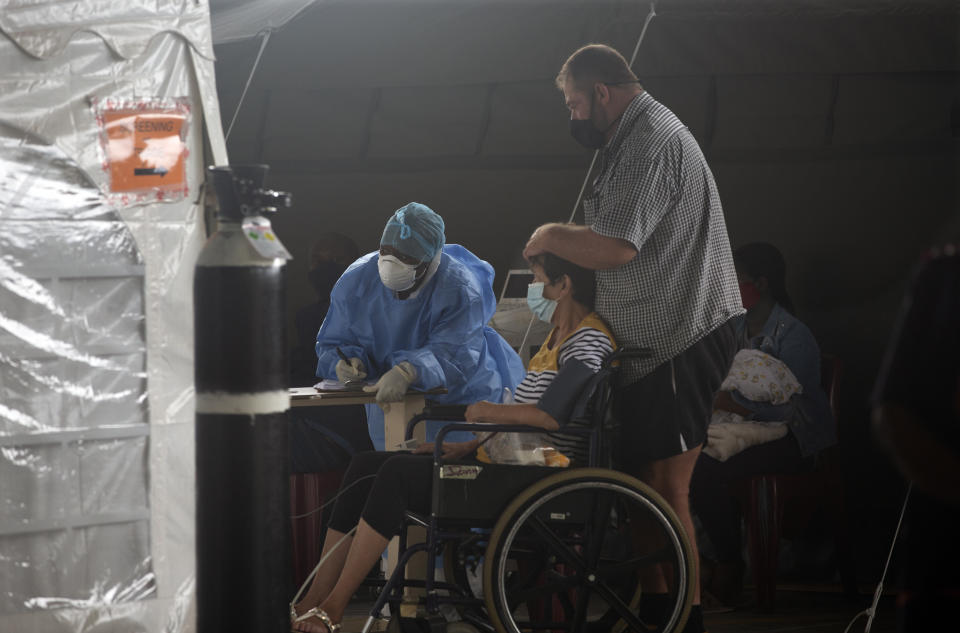 A patient is attended to at the Steve Biko Academic Hospital's outside parking area in Pretoria, South Africa, Monday, Jan. 11, 2021. As the numbers of new confirmed cases rise, South Africa's hospitals are exceeding capacity, according to health officials. (AP Photo/Denis Farrell)