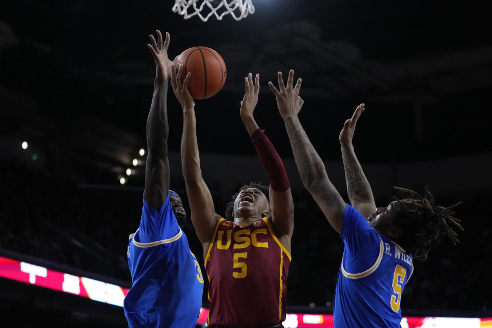 Southern California guard Boogie Ellis, center, shoots against UCLA forward Adem Bona, left, and guard Brandon Williams during the first half of an NCAA college basketball game, Saturday, Jan. 27, 2024, in Los Angeles. (AP Photo/Ryan Sun)