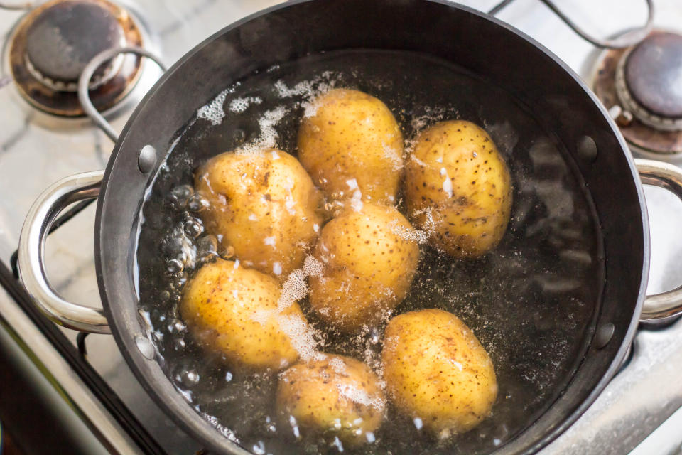 Potatoes boiling in a saucepan on a gas stove.