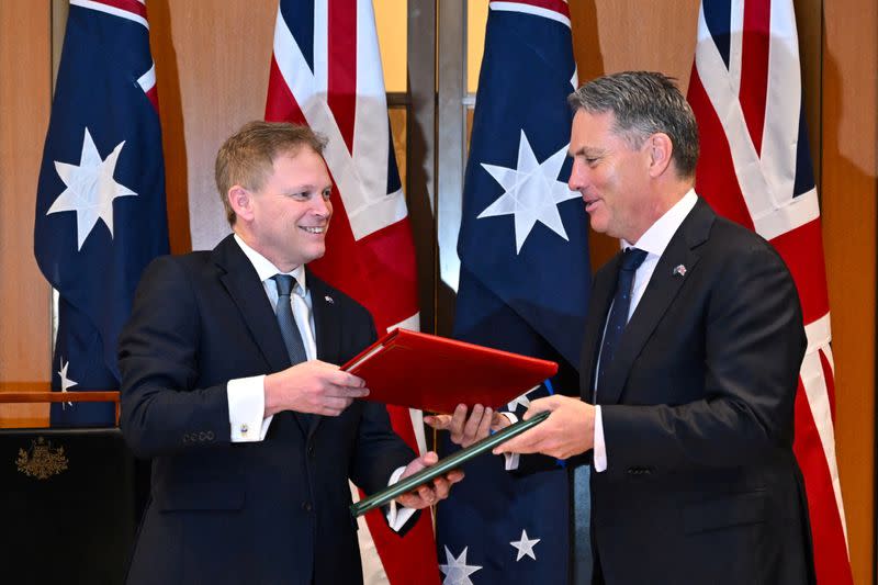 Secretary of State for Defence of the UK Shapps and Australian Defence Minister Marles exchange Defence Treaty documents during a meeting in Canberra
