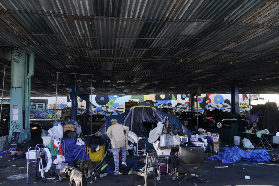 A woman gathers possessions to take before a homeless encampment was cleaned up in San Francisco, Tuesday, Aug. 29, 2023. Cities across the U.S. are struggling with and cracking down on tent encampments as the number of homeless people grows, largely due to a lack of affordable housing. Homeless people and their advocates say sweeps are cruel and costly, and there aren't enough homes or beds for everyone. (AP Photo/Jeff Chiu)