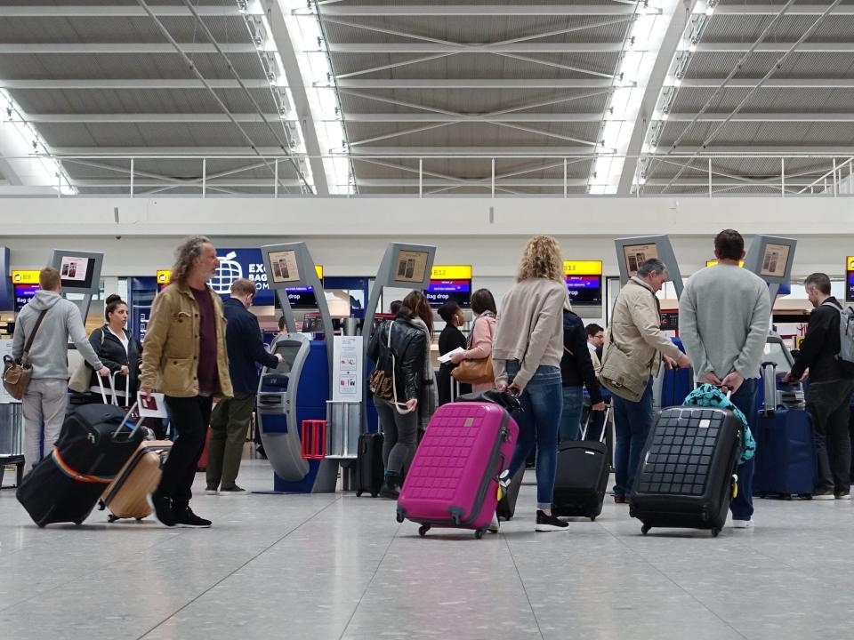 People wait in line to check in for a flight at Heathrow Airport, London