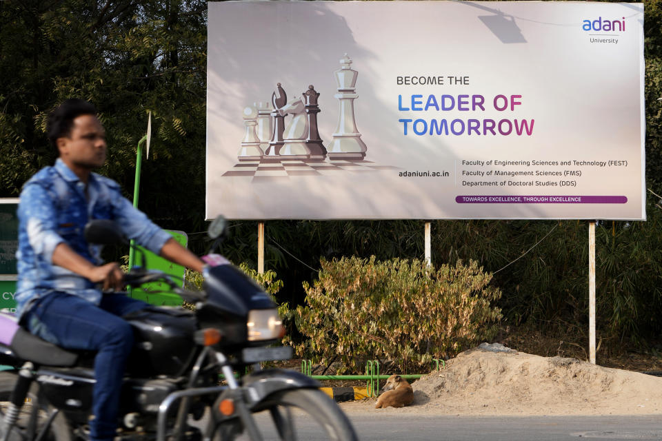A motorist rides past a hoarding of Adani University near the corporate headquarters of Adani Group in Ahmedabad, India, Friday, Jan. 27, 2023. Shares in India’s Adani Group plunged up to 20% on Friday and the company said it was considering legal action against U.S.-based short-selling firm Hindenburg Research for allegations of stock market manipulation and accounting fraud that have led investors to dump its stocks. (AP Photo/Ajit Solanki)