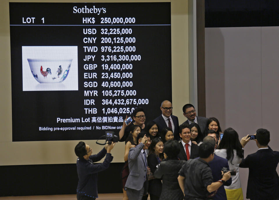 Staff members of Sotheby’s take a group picture after the auction of Meiyintang “Chicken Cup” from the Chinese Ming Dynasty (1368-1644), in Hong Kong, Tuesday, April 8, 2014. Sotheby’s said Shanghai collector Liu Yiqian won the bidding for the “Chicken Cup,” which is decorated with a rooster, hen and their chicks. Including the auction house’s commission, the price for the small cup comes to HK$281.2 million (US$36.1 million), which Sotheby’s said is a world record price for Chinese porcelain. (AP Photo/Vincent Yu)