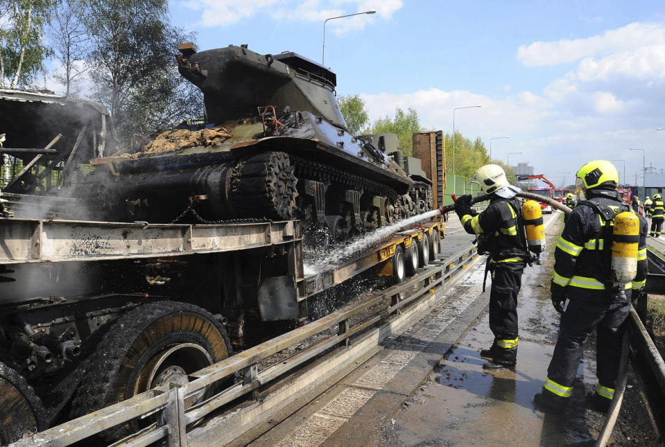In this handout photo provided by Hasicsky Zachrany Sbor or HZS Praha, Czech Republic's firefighters put out the flames at the scene of a crash in Prague, Czech Republic, Thursday, May 2, 2019. Czech firefighters and police say a bus with prisoners caught fire after colliding with two trucks, one of them carrying two tanks. The Prague rescue service says one person has died in the crash that occurred on Thursday on a busy ring road that leads to Prague's international airport. (HZS Praha via AP)