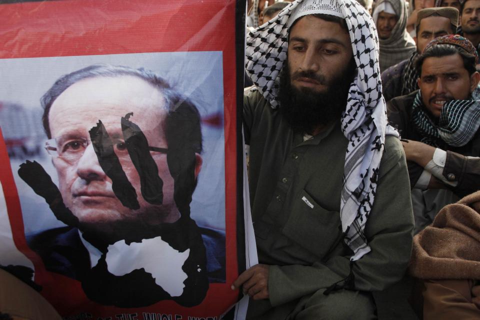 A man holds a poster during a protest against Charlie Hebdo, which featured a cartoon of the Prophet Mohammad as the cover of its first edition since an attack by Islamist gunmen, in Quetta