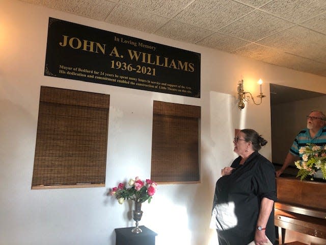 Penny May, president of Little Theatre of Bedford, reads the dedication plaque June 23 naming the lobby for John A. Williams, former Bedford mayor and longtime supporter of Little Theatre.