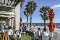 Diners are seen at a restaurant looking out towards St. Kilda Beach in Melbourne, Australia, Wednesday, Oct. 28, 2020. Melbourne, Australia's former coronavirus hot spot, emerged from a lockdown at midnight Tuesday, restaurants, cafes and bars were allowed to open and outdoor contact sports can resume. (AP Photo/Asanka Brendon Ratnayake)