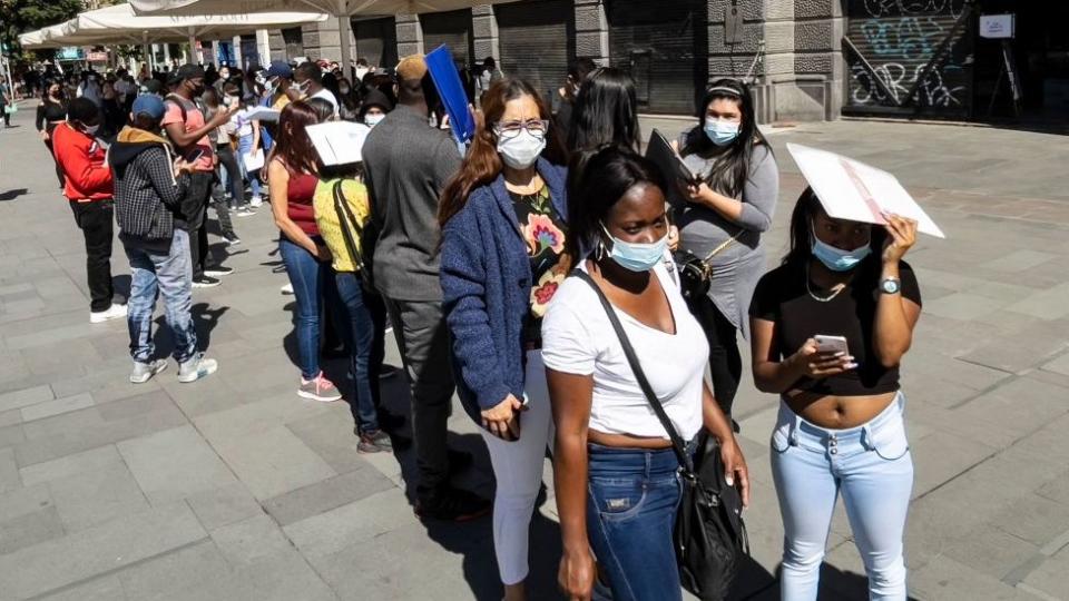 Extranjeros haciendo fila para regularizar su situación migratoria.