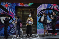 People wearing face masks to help curb the spread of the coronavirus wait outside a bakery in Hong Kong, Monday, Nov. 30, 2020. (AP Photo/Kin Cheung)