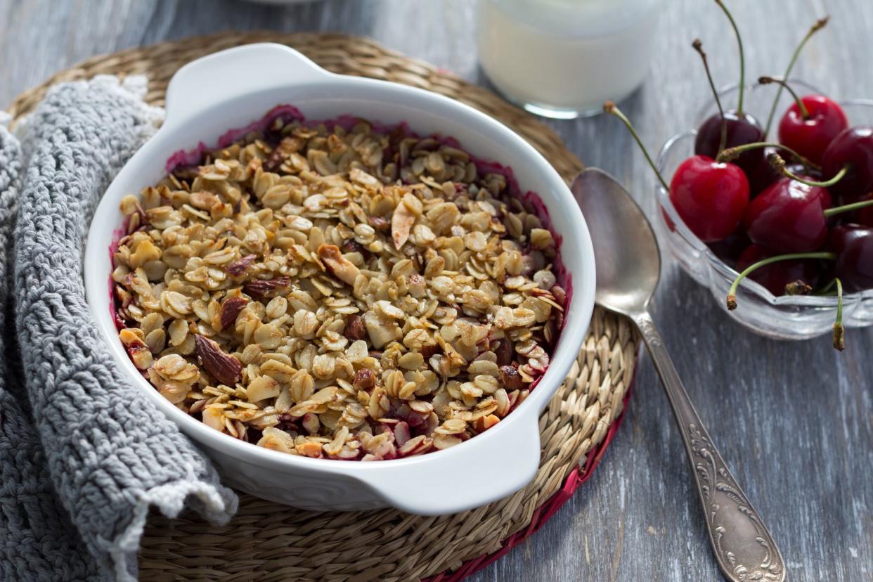 Homemade cherry crumble with oatmeal and almonds with fresh cherry and yogurt on a light wooden table