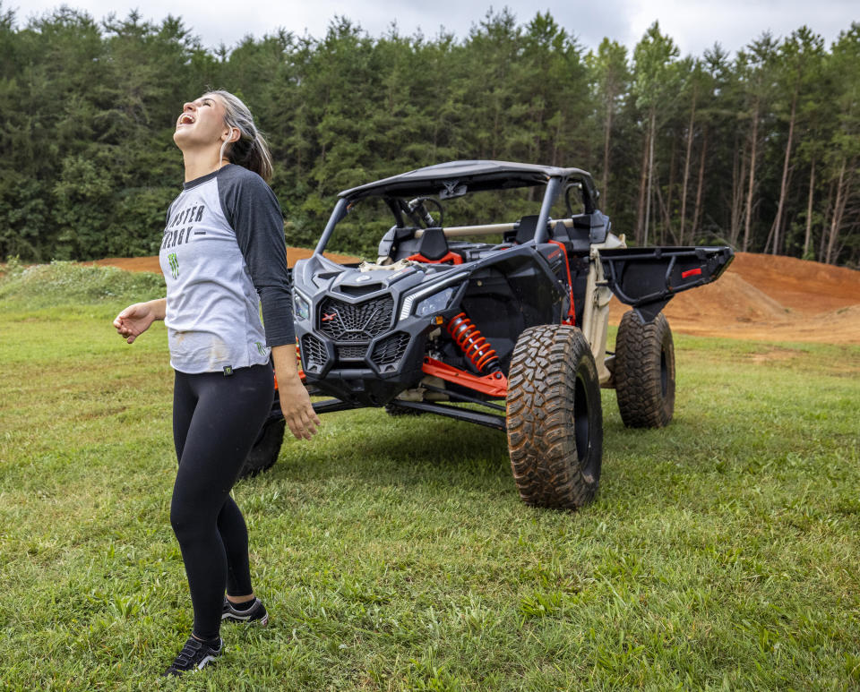 In this photo provided by Can Am Off-Road, Hailie Deegan laughs next to Can-Am Maverick X3 on the track she carved into the front yard of her first home, in Denver, N.C., on Aug. 30. 2022. Deegan is the only full-time female driver at the NASCAR national level but her future is unclear after Friday night’s Truck Series season finale. (Can Am Off-Road via AP)