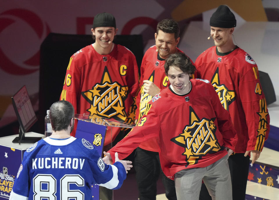 Quinn Hughes of Team Hughes, second from right, picks Nikita Kucherov (86) as fellow team members, from left, Jack Hughes, Michael Buble and Elias Pettersson look on during the NHL All-Star hockey week draft in Toronto on Thursday, Feb. 1, 2024. (Nathan Denette/The Canadian Press via AP)