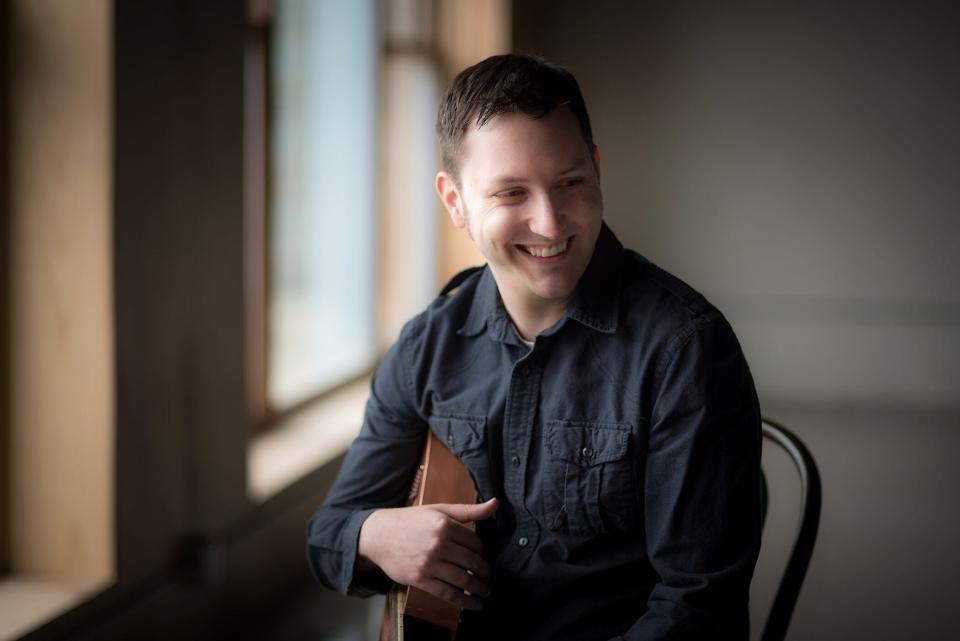 Zachary Scot Johnson, creator of the YouTube channel thesongadayproject, poses with his guitar.