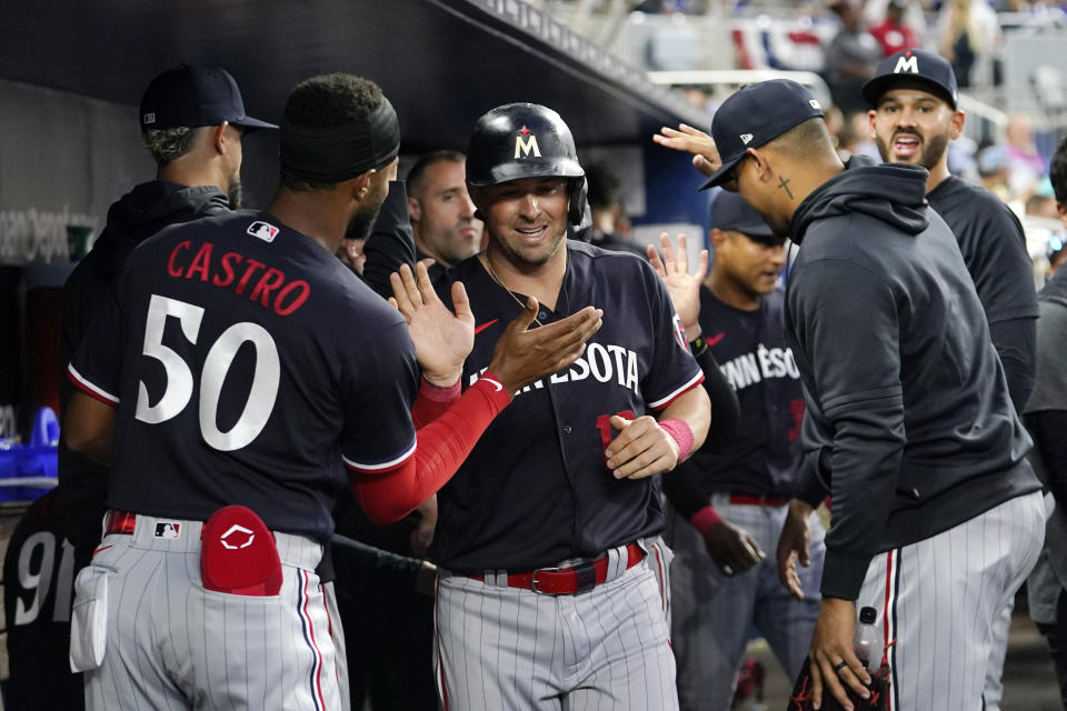 Minnesota Twins' Kyle Farmer is congratulated in the dugout after scoring on a double hit by Carlos Correa during the fourth inning of a baseball game against the Miami Marlins, Monday, April 3, 2023, in Miami. (AP Photo/Lynne Sladky)