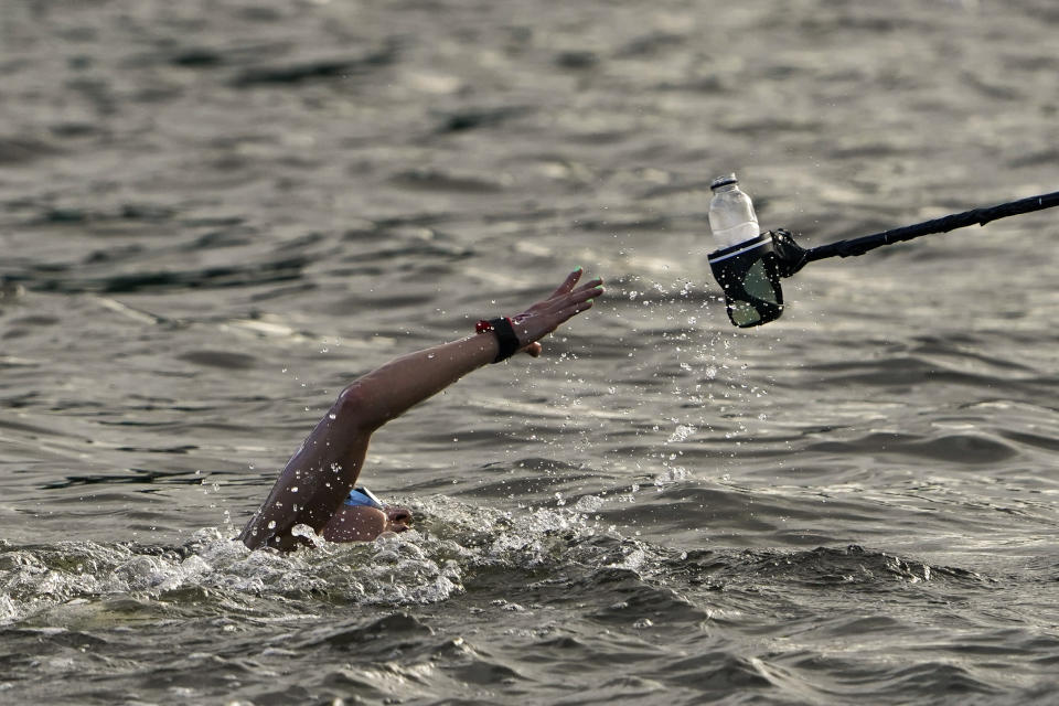 Souad Nefissa Cherouati, of Algeria, grabs a drink at a feeding station during the women's marathon swimming at the 2020 Summer Olympics, Wednesday, Aug. 4, 2021, in Tokyo, Japan. (AP Photo/Jae C. Hong)