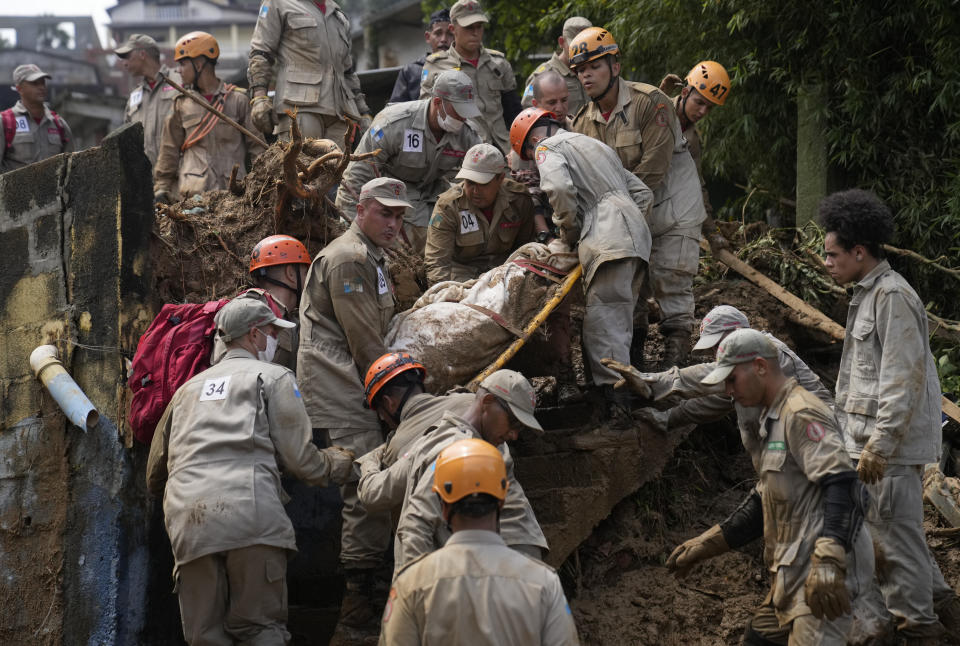 Rescue workers remove the body of a mudslide victim in Petropolis, Brazil, Wednesday, Feb. 16, 2022. Extremely heavy rains set off mudslides and floods in a mountainous region of Rio de Janeiro state, killing multiple people, authorities reported. (AP Photo/Silvia Izquierdo)