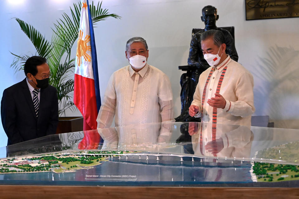 Philippine Foreign Affairs Secretary Enrique Manalo, center, and Chinese Foreign Minister Wang Yi, right, unveil a scale model of a bridge project at the Department of Foreign Affairs in Manila, Philippines on Wednesday, July 6, 2022. (Jam Sta Rosa/Pool Photo via AP)