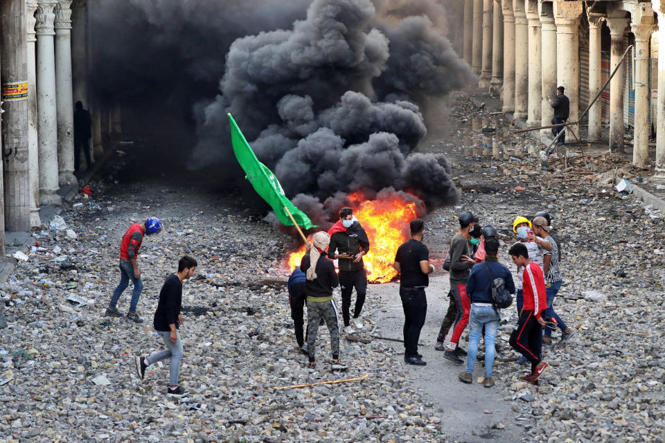 Anti-government protesters set fire while security forces close Rasheed Street during clashes in Baghdad, Iraq, Thursday, Nov. 28, 2019. Scores of protesters have been shot dead in the last 24 hours, amid spiraling violence in Baghdad and southern Iraq, officials said. (AP Photo/Khalid Mohammed)