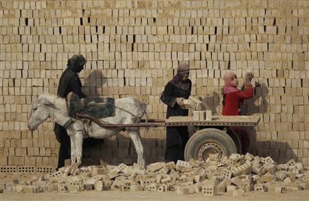 Female workers load bricks on a donkey-driven cart at a brick factory in the town of Nahrawan, east of Baghdad, in this March 8, 2012 file photo. REUTERS/Thaier al-Sudani/Files