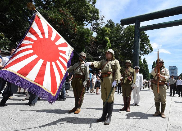 Men clad in Japanese Imperial Army and Navy uniforms stand at attention at the entrance of the Yasukuni shrine, in Tokyo, on August 15, 2014, on the 69th anniversary of Japan's surrender in World War II