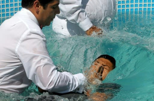 "Do you believe in Jesus Christ?" a minister asked newly baptized members, who responded "Amen!" with their right hands raised before being plunged into the full-body baptismal pools