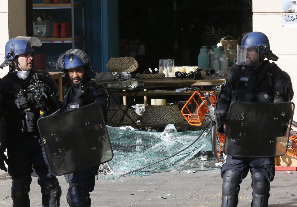 Police stand next to a damaged shop at the Place de Republique during a yellow vest demonstration in Paris, Saturday, April 20, 2019. French yellow vest protesters are marching anew to remind the government that rebuilding the fire-ravaged Notre Dame Cathedral isn't the only problem the nation needs to solve. (AP Photo/Michel Euler)