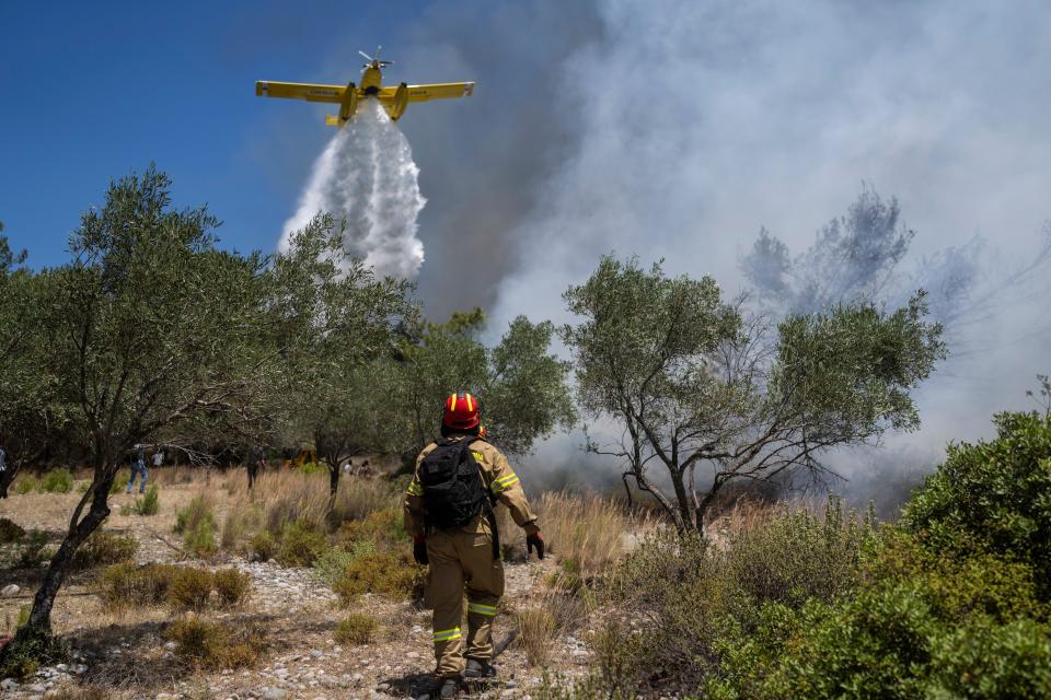 An aircraft drops water over a wildfire in Vati village, on the Aegean Sea island of Rhodes, southeastern Greece, on Tuesday, July 25, 2023. A third successive heat wave in Greece pushed temperatures back above 40 degrees Celsius (104 degrees Fahrenheit) across parts of the country Tuesday following more nighttime evacuations from fires that have raged out of control for days. (AP Photo/Petros Giannakouris)