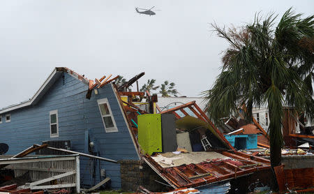 A military helicopter flies over a destroyed house after Hurricane Harvey struck in Rockport, Texas, August 26, 2017. REUTERS/Rick Wilking