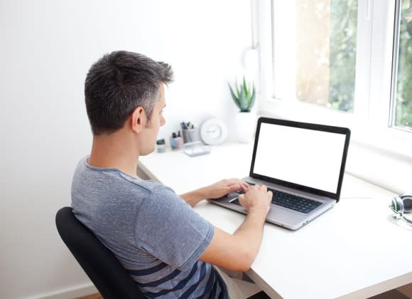 A man works on a laptop at home.