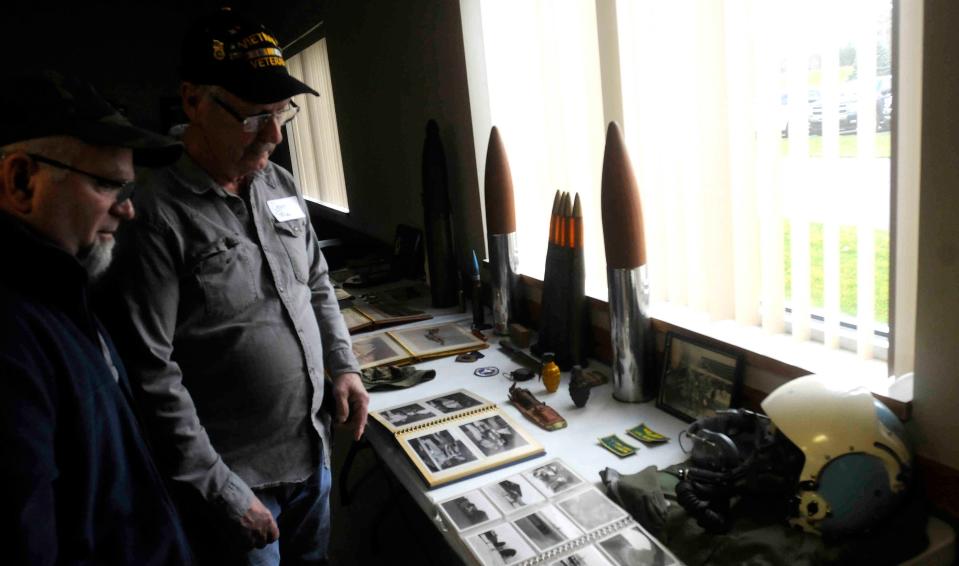 Joe Edwards and Dean Pace of Mansfield, look at Carl Reichert's display during the Ashland area Vietnam veterans reunion Saturday.