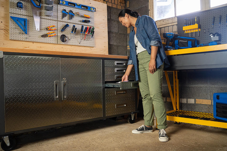 Woman organizing tools in her garage using Mastercraft storage cabinet