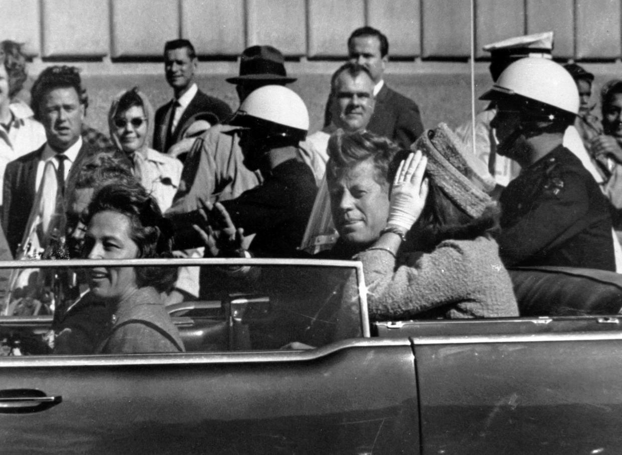 President John F. Kennedy is seen riding in motorcade approximately one minute before he was shot in Dallas, Tx., on Nov. 22, 1963. In the car riding with Kennedy are Mrs. Jacqueline Kennedy, right, Nellie Connally, left, and her husband, Gov. John Connally of Texas. (AP Photo/Jim Altgens)