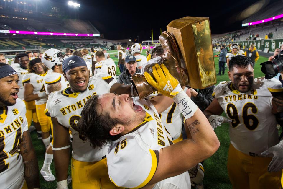 University of Wyoming senior linebacker Adam Pilapil (45) imitates drinking from the bronze boot trophy after beating rival Colorado State University on Friday, Oct. 26, 2018, at Canvas Stadium in Fort Collins, Colo.