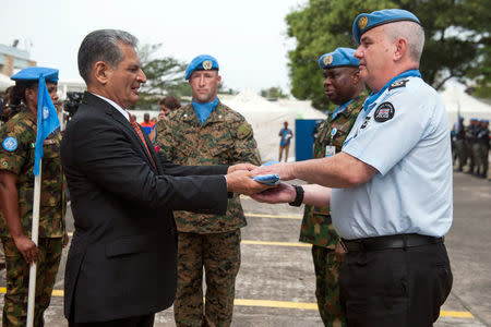 Farid Zarif, the Special Representative of the Secretary-General and Head of UNMIL, presents the UN flag to Simon Blatchly, UNMIL Police Commissioner from United Kingdom, during the ceremony at UNMIL headquarters in Monrovia to honour and farewell the police and military personnel who served with the United Nations Mission in Liberia (UNMIL) February 5, 2018. Albert Gonzalez Farran/UNMIL/Handout via REUTERS