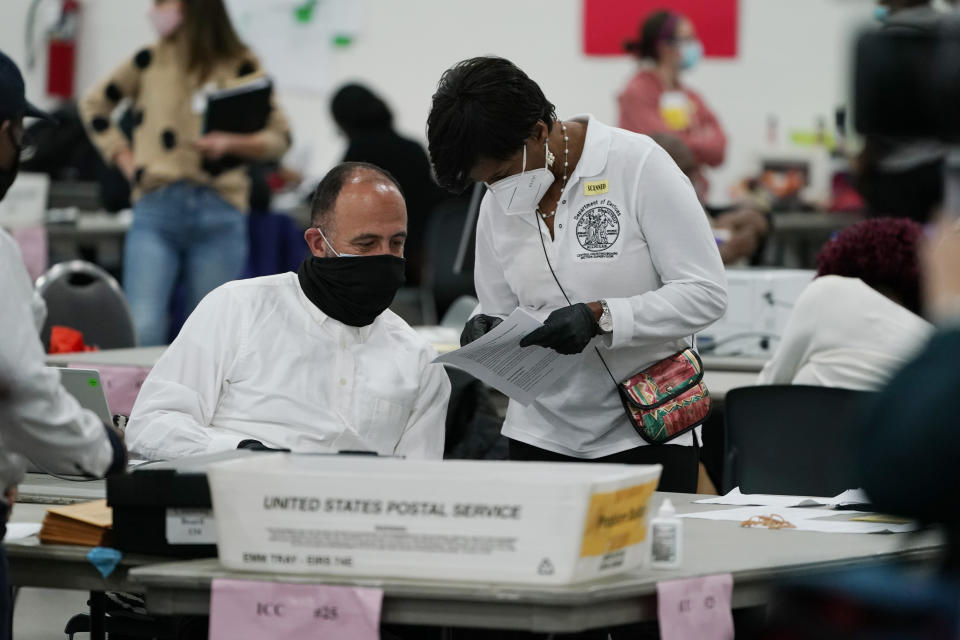 FILE - In this Wednesday, Nov. 4, 2020 file photo, a worker checks with an election supervisor at the central counting board in Detroit. On Friday, Feb. 12, 2021, The Associated Press reported on a video circulating online incorrectly asserting it shows tens of thousands of illegal ballots delivered 8 hours after the election night deadline at the TCF Center in Detroit. But it shows the city delivering legal ballots to be counted, as expected. The 8 p.m. deadline on Election Day Nov. 2, 2020, was for voters to cast their ballots, not for those ballots to be delivered or counted. (AP Photo/Carlos Osorio)