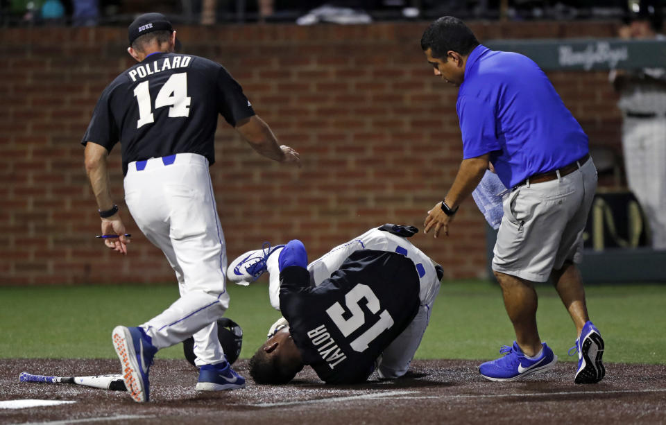 Duke's Kennie Taylor (15) rolls on the ground after being hit on the face by a pitch, while coach Chris Pollard and a trainer run to his aid during the first inning of the team's NCAA college baseball tournament super regional game against Vanderbilt on Saturday, June 8, 2019, in Nashville, Tenn. (AP Photo/Wade Payne)