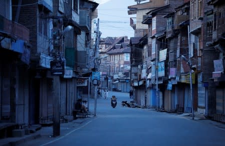 Kashmiri girls ride a scooter on a deserted road during restrictions after scrapping of the special constitutional status for Kashmir by the Indian government, in Srinagar