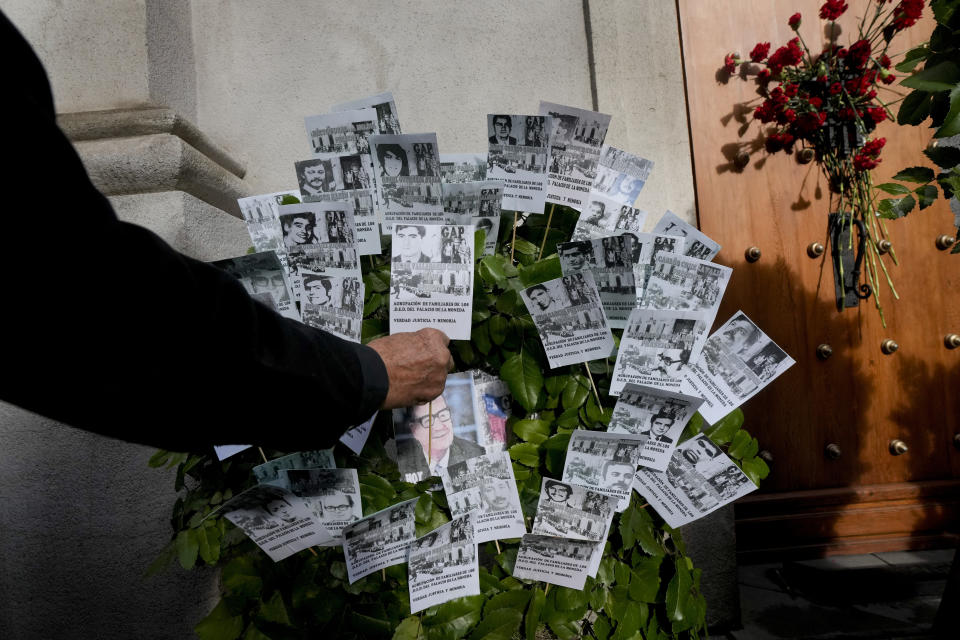 Una persona coloca una tarjeta de recuerdo en la puerta lateral este del palacio presidencial de La Moneda, a través de la cual el cuerpo del presidente Salvador Allende fue transportado por soldados y bomberos hace 50 años después del golpe militar que derrocó a su gobierno en Santiago, Chile, el lunes 11 de septiembre de 2023. (AP Foto/Esteban Félix)