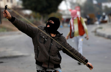 A masked Palestinian demonstrator uses a slingshot to hurl stones towards Israeli troops during clashes at a protest against U.S. President Donald Trump's decision to recognise Jerusalem as the capital of Israel, near the West Bank city of Nablus, December 29, 2017. REUTERS/Mohamad Torokman