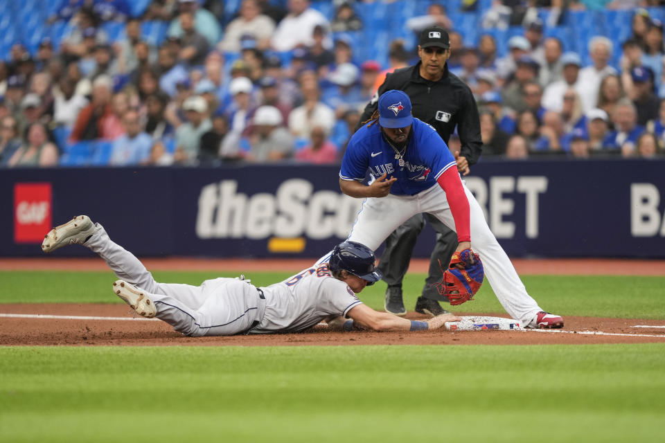 Houston Astros' Jake Meyers (6) slides back into first base as Toronto Blue Jays' Vladimir Guerrero Jr., front right, attempts to tag him out in first-inning baseball game action in Toronto, Ontario, Monday, June 5, 2023. (Andrew Lahodynskyj/The Canadian Press via AP)