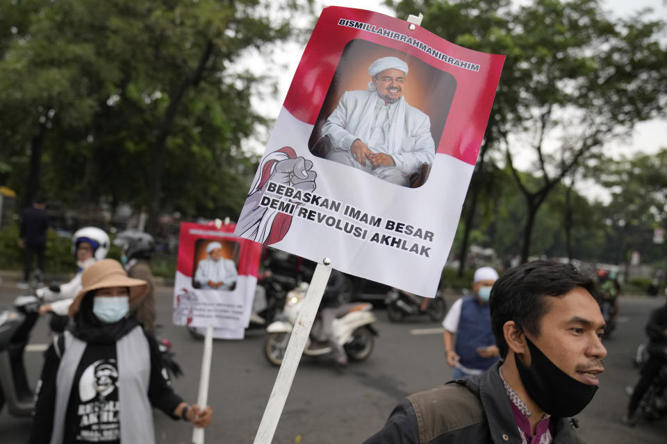 Supporter holds posters bearing a portrait of firebrand cleric Rizieq Shihab during a rally near the district court where his sentencing hearing is held in Jakarta, Indonesia, Thursday, June 24, 2021. The influential cleric was sentenced to another four years in prison on Thursday for concealing information about his coronavirus test result. Writings on the poster read "Free our grand imam for moral revolution." (AP Photo/Dita Alangkara)