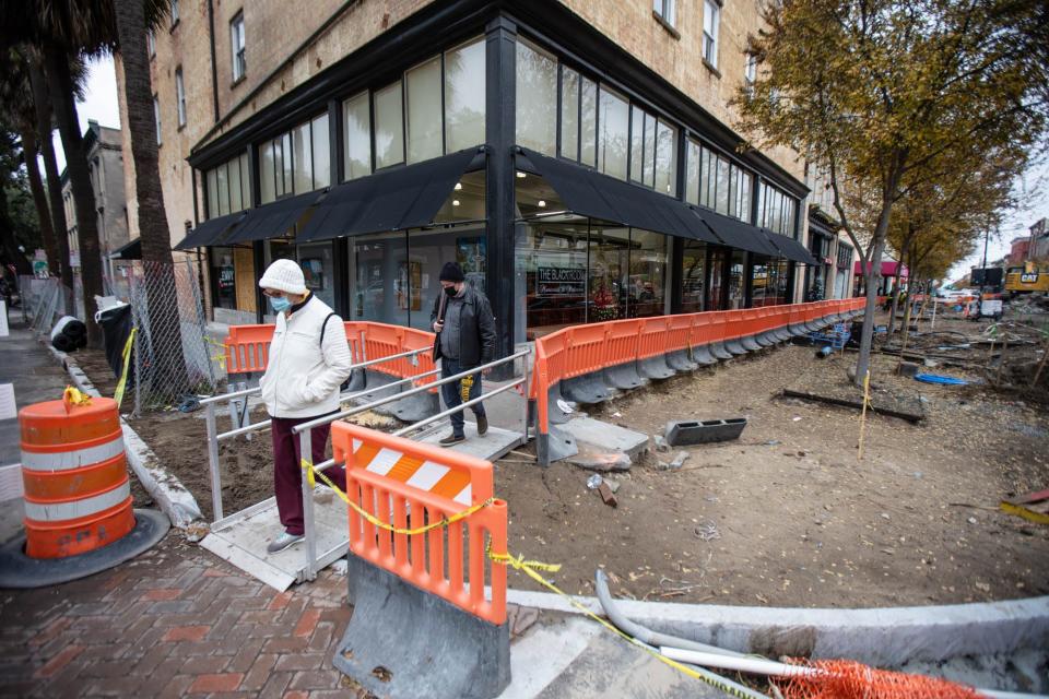 Visitors use a temporary walkway near Envy Nail Bar as they make their way  through the construction for the Broughton streetscapes project.