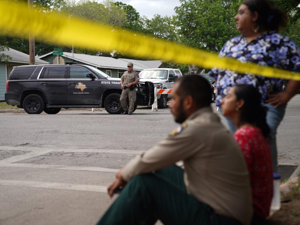 People sit on the curb outside of Robb Elementary School as State troopers guard the area in Uvalde, Texas, on May 24, 2022.