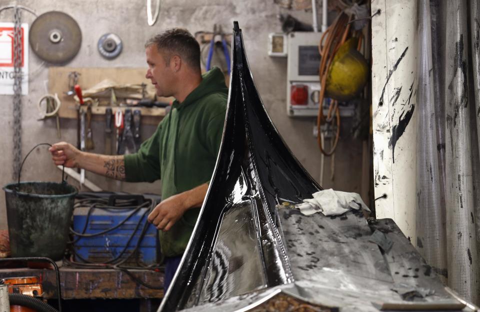 A worker prepares materials for gondola maintenance at the San Trovaso boatyard known as a