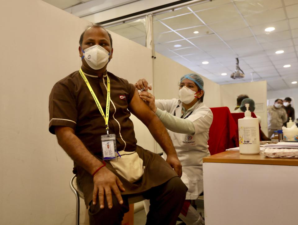A health worker, left, receives a COVID-19 vaccine at a private Hospital in New Delhi, India, Saturday, Jan. 16, 2021. India started inoculating health workers Saturday in what is likely the world's largest COVID-19 vaccination campaign, joining the ranks of wealthier nations where the effort is already well underway. (AP Photo/Manish Swarup)