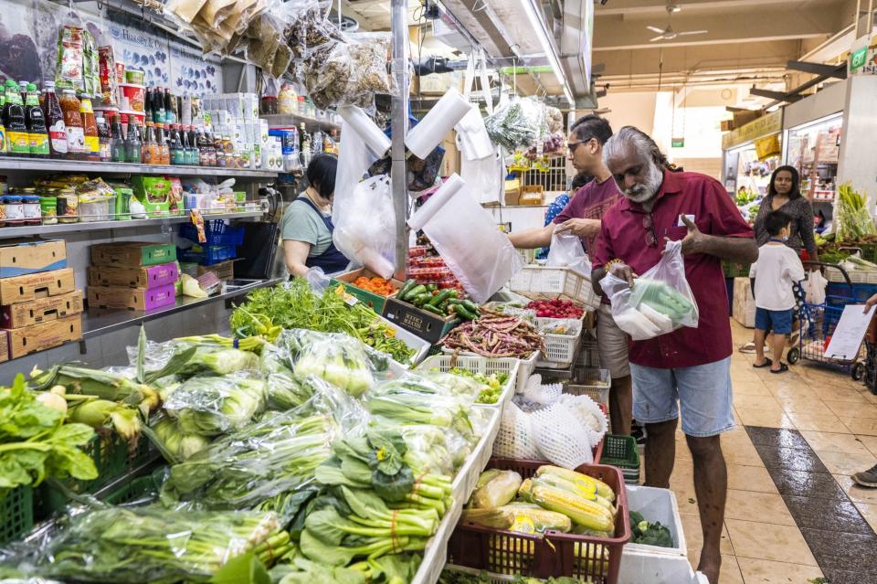 A customer pays for fresh produce at Tekka Center in Singapore, on Saturday, April 22, 2023.  (EDWIN KOO/Bloomberg)