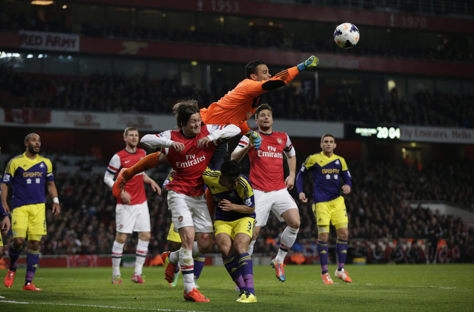 Swansea City's goalkeeper Michel Vorm punches the ball clear above Neil Taylor, 3, and Arsenal's Tomas Rosicky, center bottom left, during the English Premier League soccer match between Arsenal and Swansea City's at the Emirates Stadium in London, Tuesday, March 25, 2014. (AP Photo/Matt Dunham)