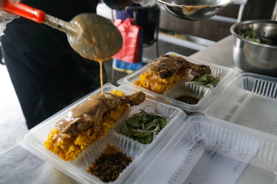 Ayu Yusoff packs food to go for customers at Quallys Nusantara Kitchen on Jalan Burmah, George Town on September 21, 2021.