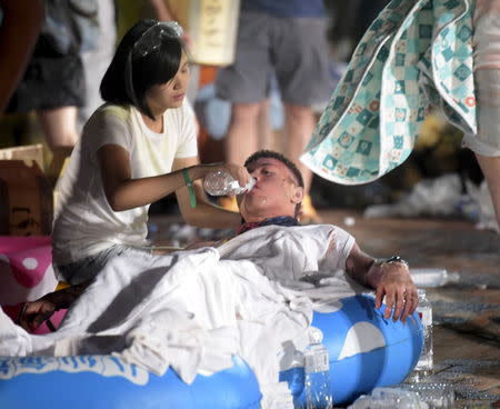 A person helps an injured victim from an accidental explosion during a music concert at the Formosa Water Park in New Taipei City, Taiwan, June 27, 2015. REUTERS/Wang Wei